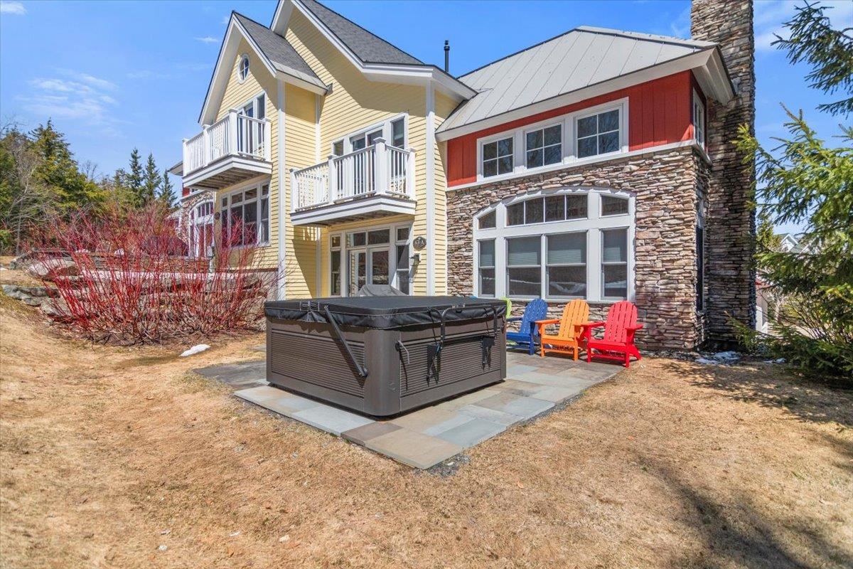 Spacious Stratton Mountain real estate backyard with private hot tub and stone patio, ideal for Vermont vacation rentals and outdoor relaxation