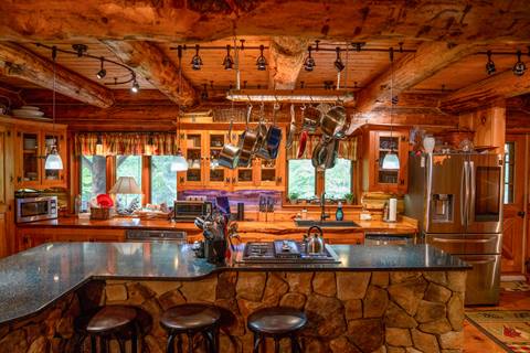 Spacious log cabin kitchen in Stratton’s Beaver Street community with exposed beams, stone island, and stainless steel appliances