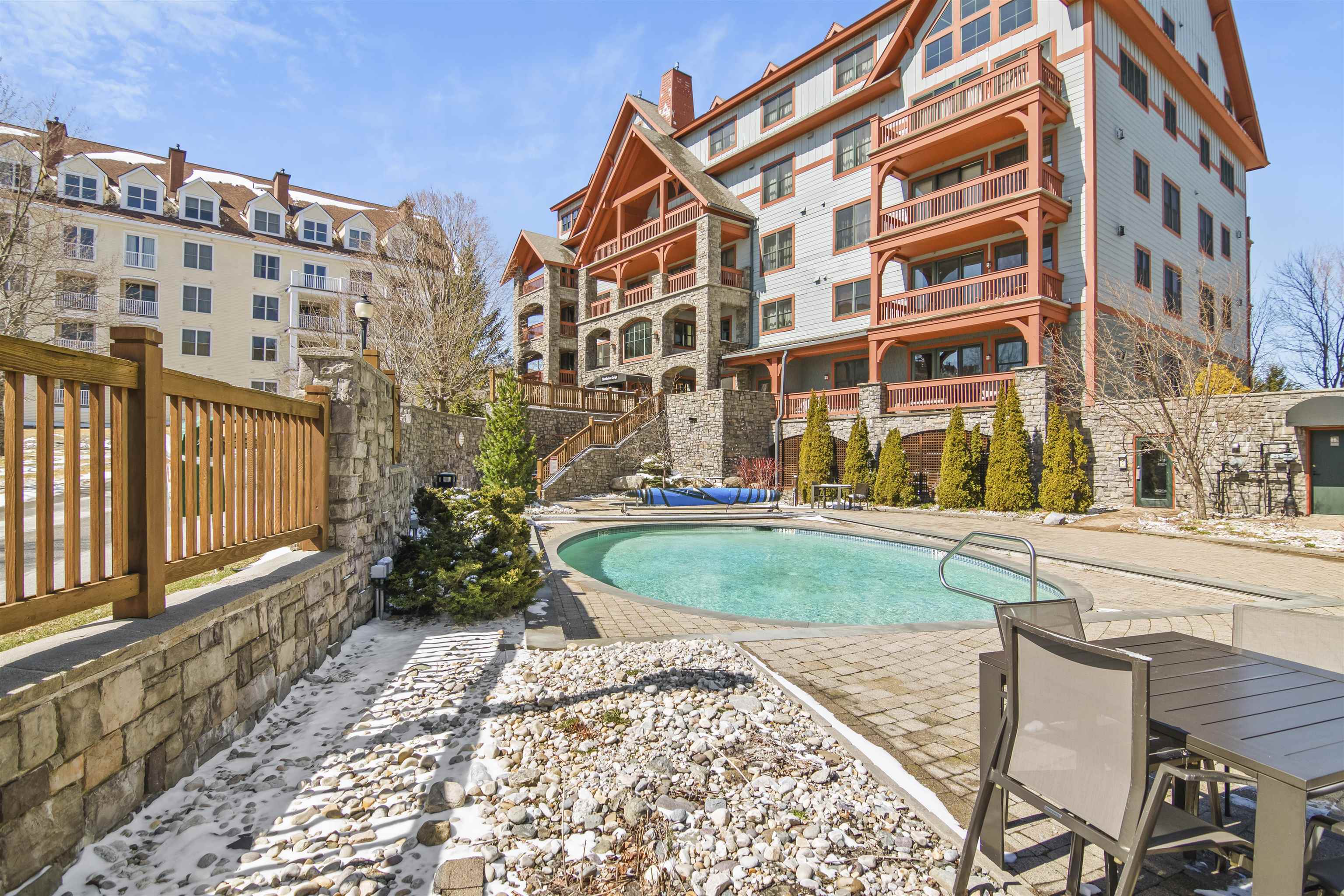 Heated outdoor pool and stone terrace at Hearthstone, part of Stratton Mountain’s premier Vermont real estate listings with year-round resort amenities