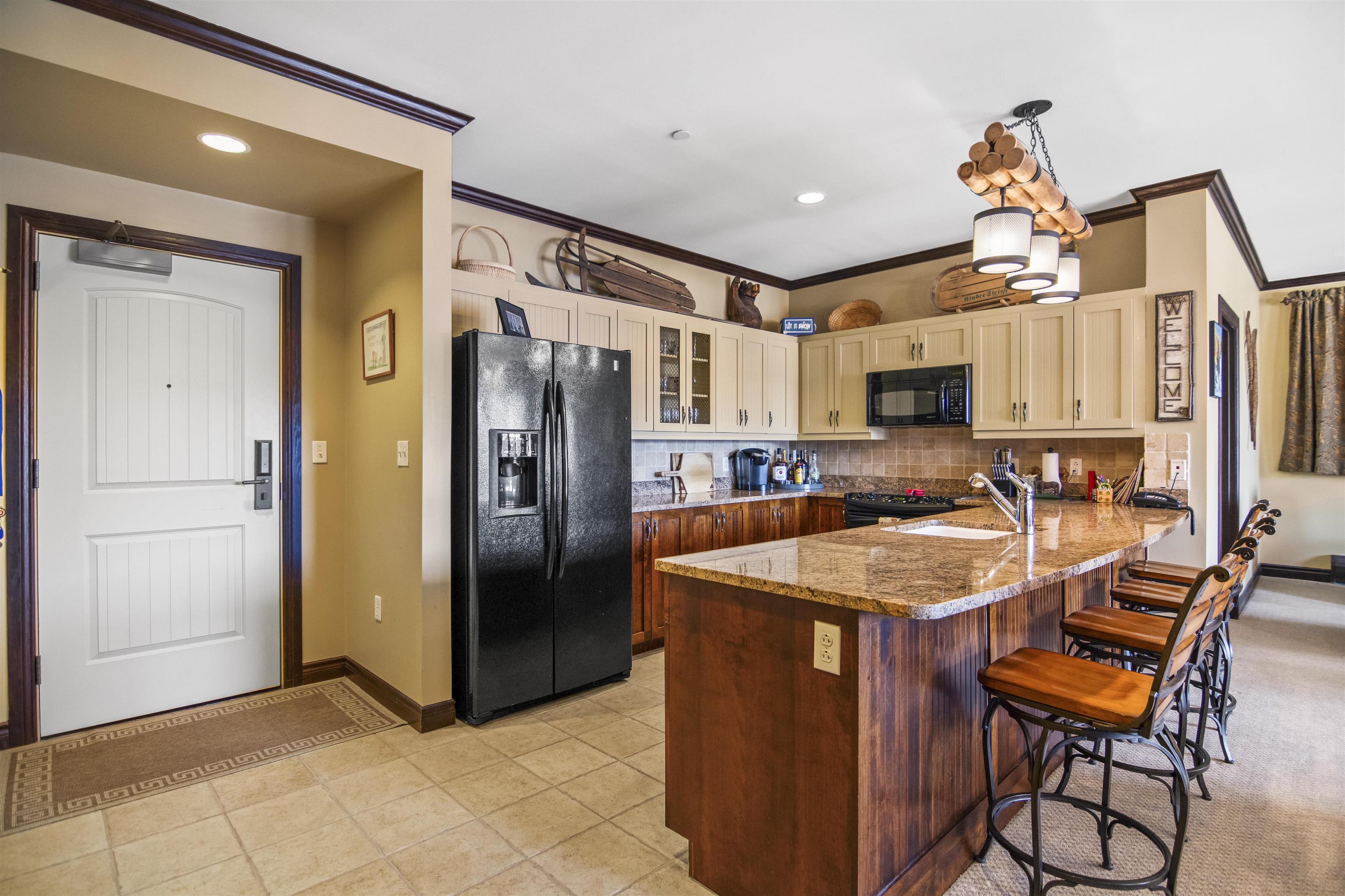 Spacious kitchen with granite island and rustic accents inside Hearthstone condo at Stratton Mountain, a move-in ready option in southern Vermont real estate