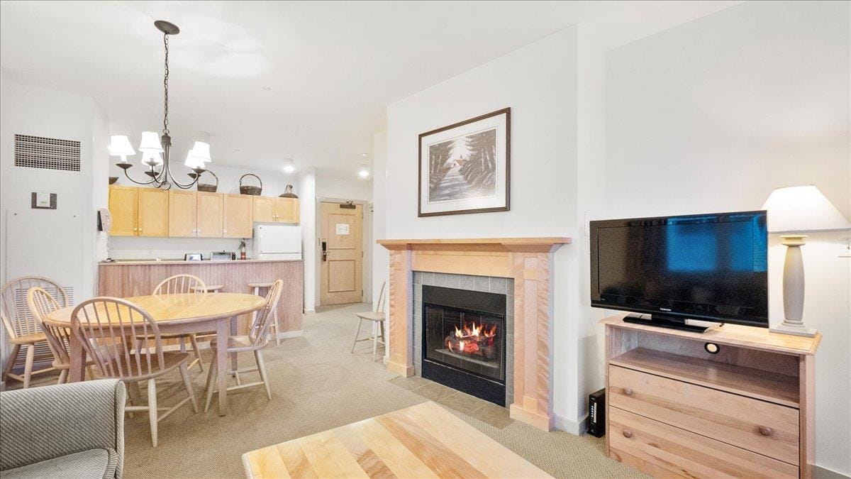 open concept vermont real estate condo living room with gas fireplace dining table and kitchenette inside long trail house at stratton mountain