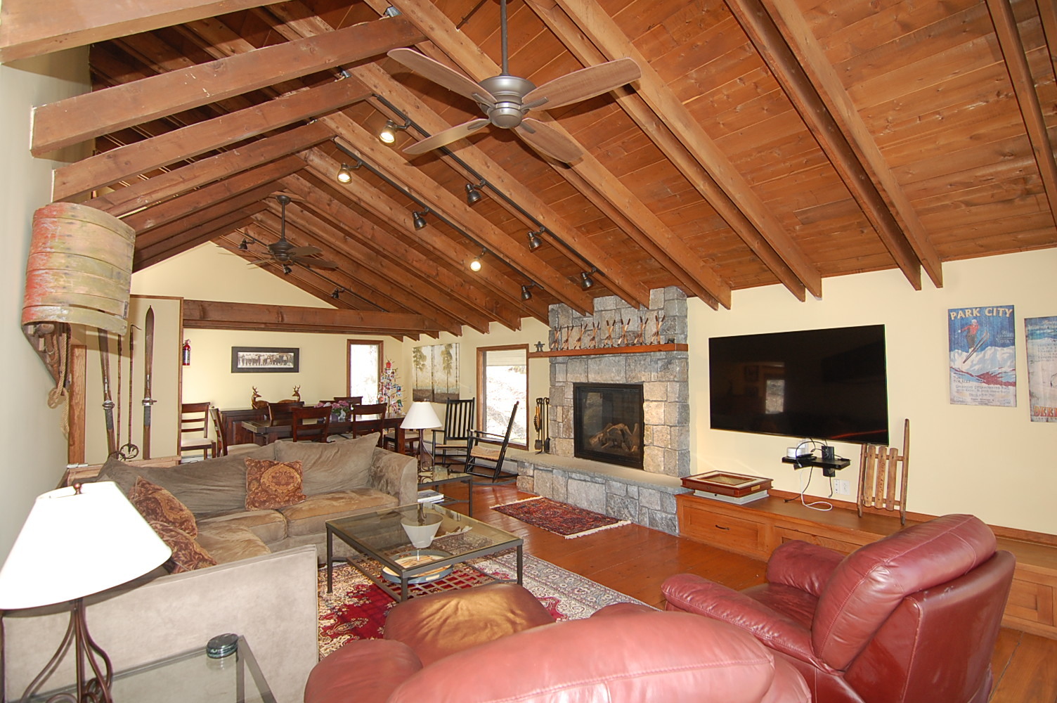 Open-concept living and dining area at North Branch rental with wood beam ceilings and stone fireplace, part of southern Vermont real estate offerings